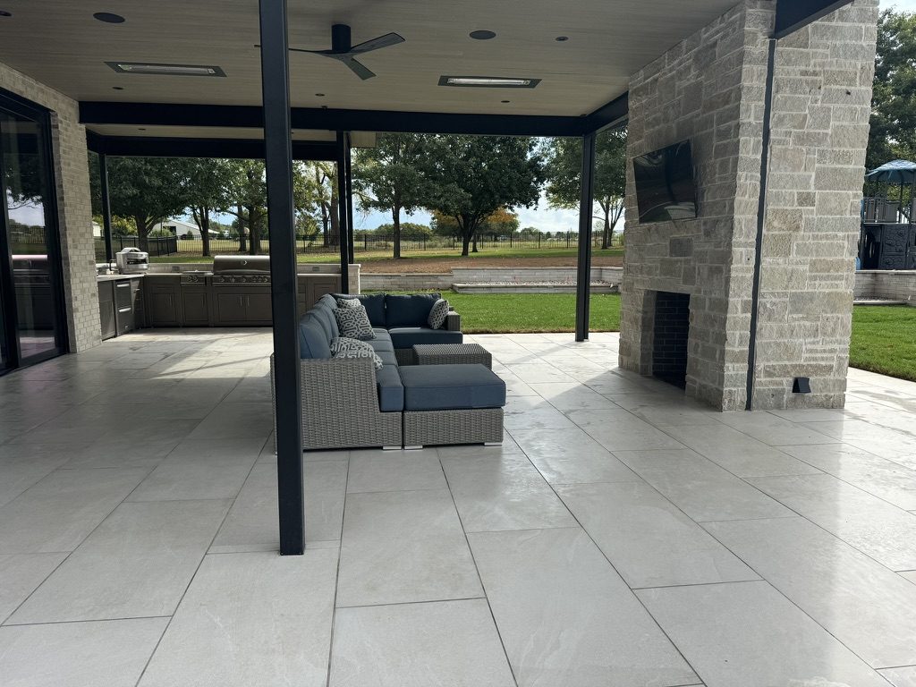 A covered outdoor living room with fireplace and kitchen