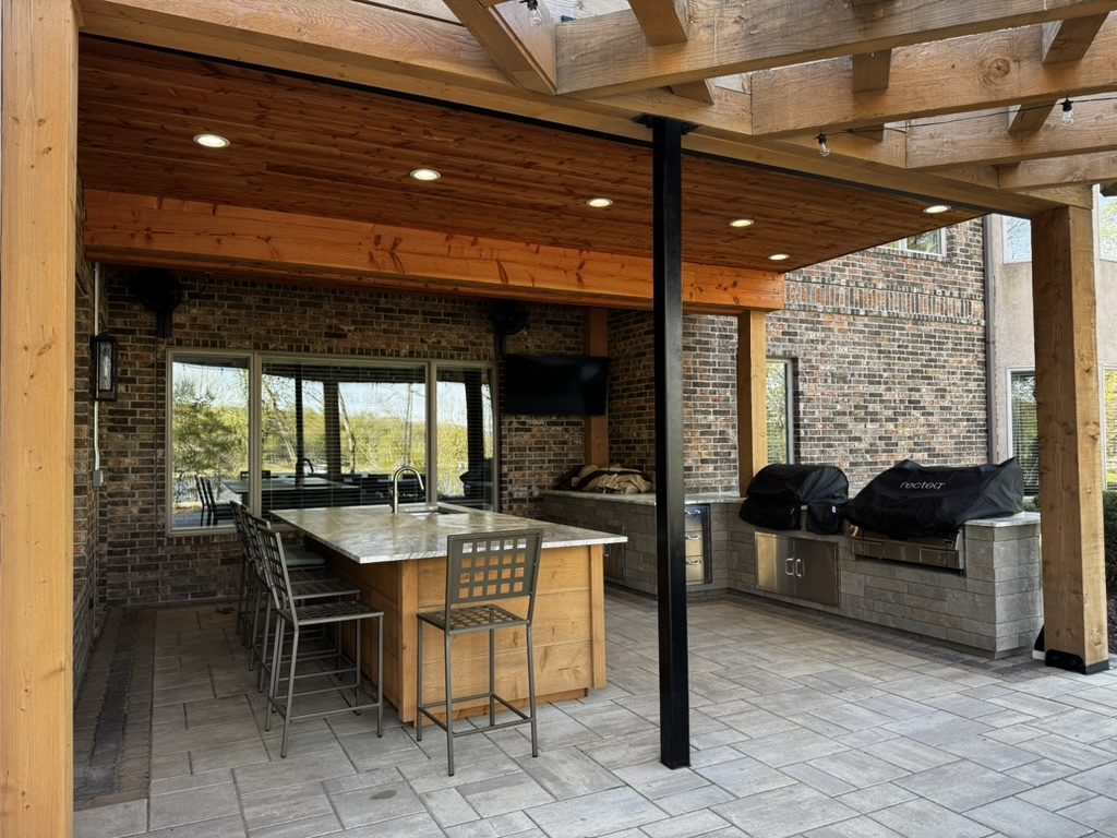 A covered outdoor kitchen with island and grills