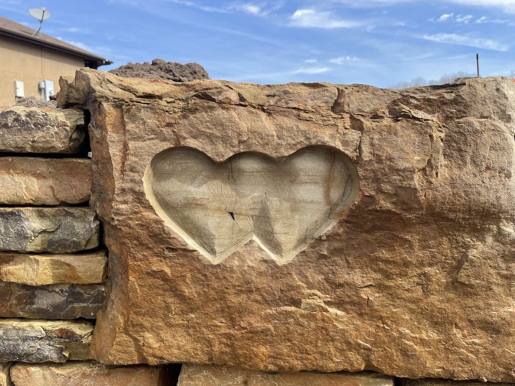 A pair of hearts hand-carved into a natural stone wall